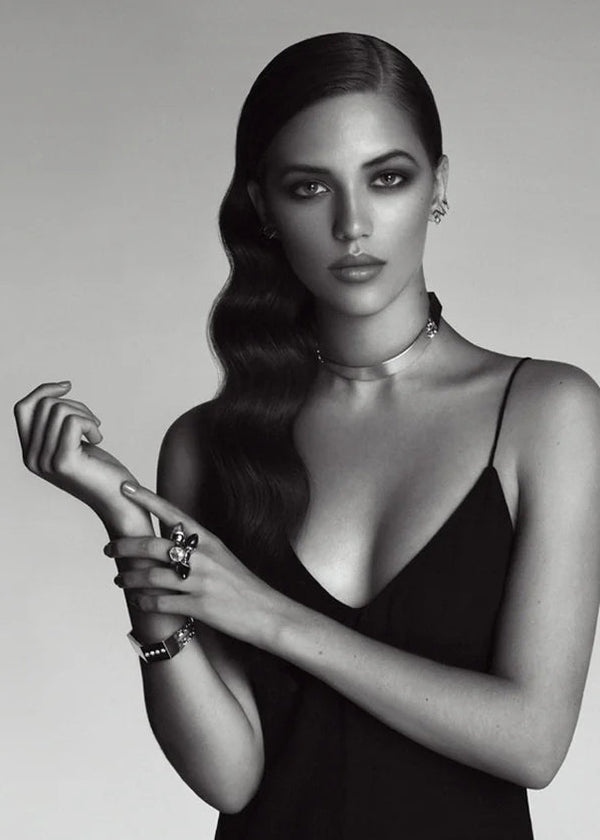 Black and white portrait of a woman wearing jewelry against a plain background